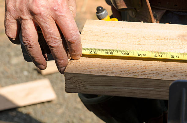 Wood siding contractor using a miter saw Wood siding contractor using a tape measure before cutting trim boards on the construction of a new home miter saw stock pictures, royalty-free photos & images