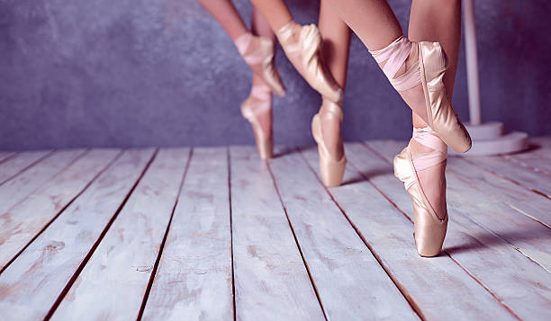 The feet of a young ballerinas in pointe shoes The close-up feet of a three young ballerinas in pointe shoes against the background of the wooden floor ballet shoe stock pictures, royalty-free photos & images