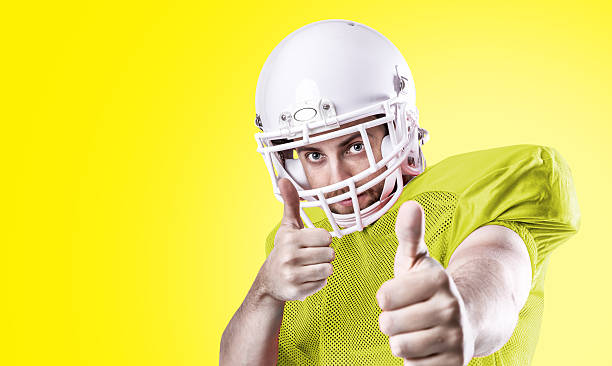 football-spieler im gelben trikot auf gelbem hintergrund - football helmet american football yellow american football uniform stock-fotos und bilder