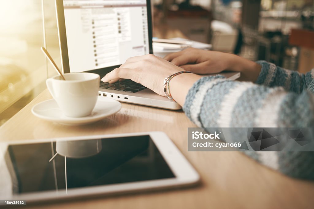 Woman using a laptop during a coffee break Woman using a laptop during a coffee break, hands close up 2015 Stock Photo