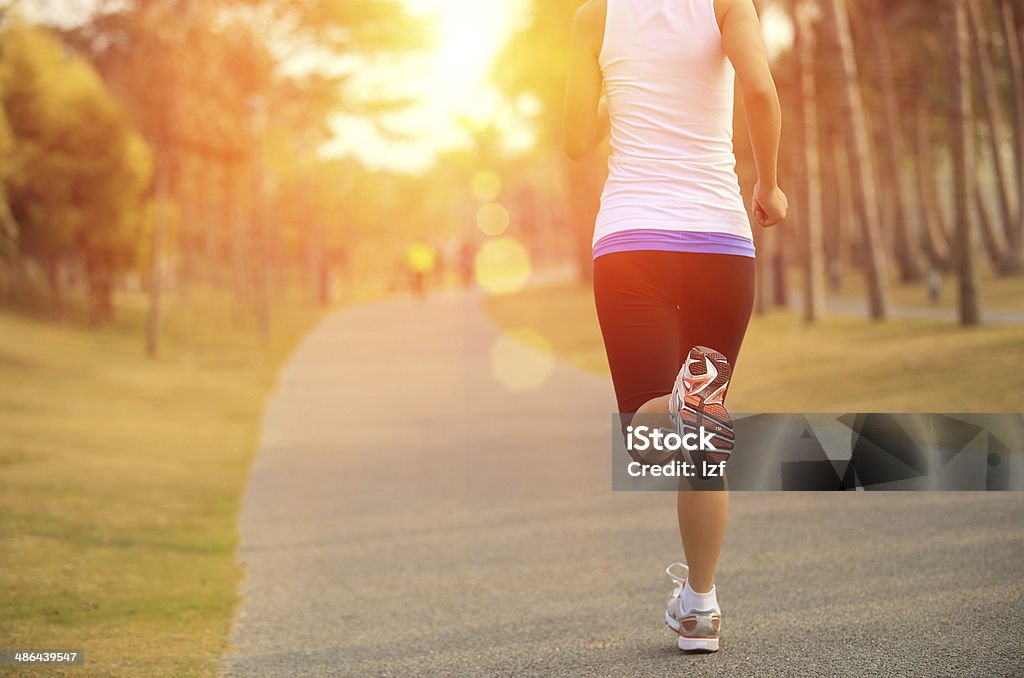 Cropped image of jogging woman, sun in background healthy lifestyle asian woman jogging at tropical park Activity Stock Photo