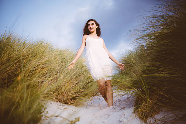 istock Girl walking through beach dunes at sunset 486443201