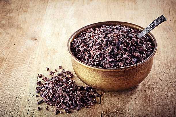 cacao nibs Bowl of cacao nibs on wooden background cacao nib stock pictures, royalty-free photos & images