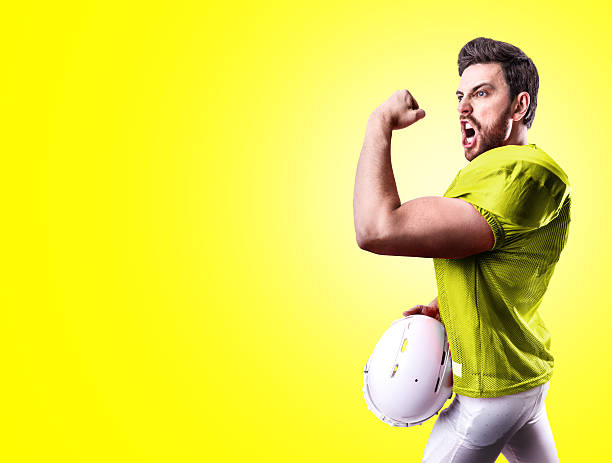 football-spieler im gelben trikot auf gelbem hintergrund - football helmet american football yellow american football uniform stock-fotos und bilder