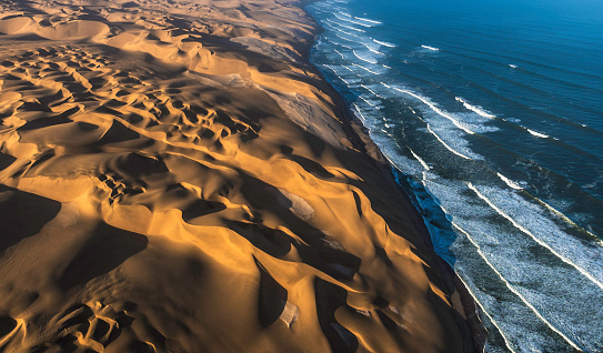 Aerial view of the sand dunes of the Namib Desert colliding with the Atlantic Ocean, Namibia.