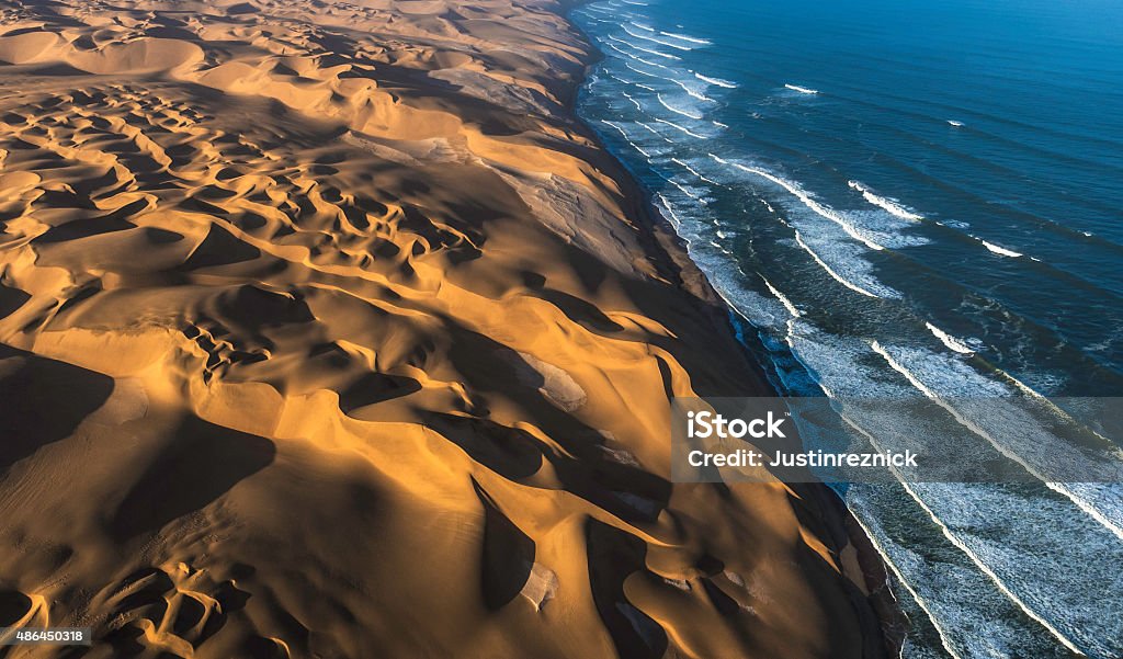 Aerial View of Sand Dunes and Ocean Aerial view of the sand dunes of the Namib Desert colliding with the Atlantic Ocean, Namibia. Namibia Stock Photo