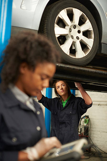 female car mechanics working under a car.