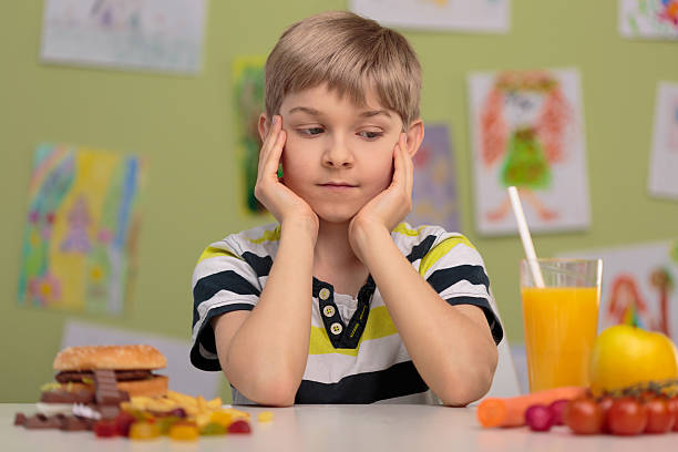 Healthy or unhealthy lunch Boy having choice - healthy or unhealthy lunch food elementary student healthy eating schoolboy stock pictures, royalty-free photos & images