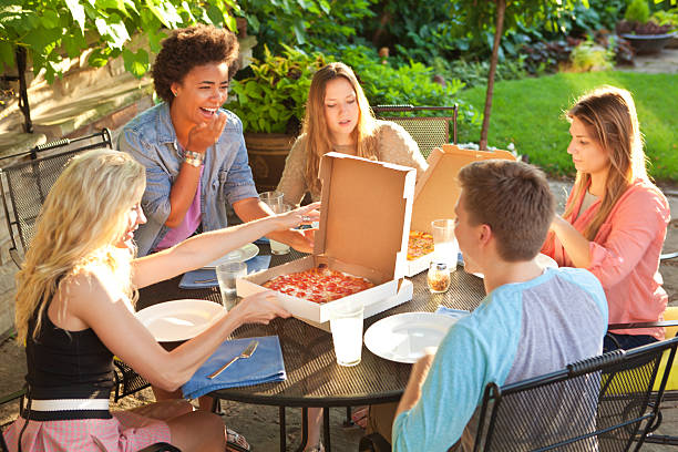 istock Teenage Friends Sharing Pizza Dinner at Summer Backyard Patio Table 486456698