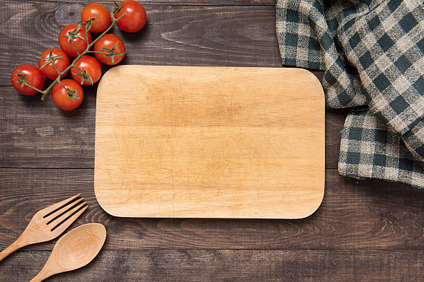 istock Cutting board with tomato, fork and spoon on wooden background 486465676