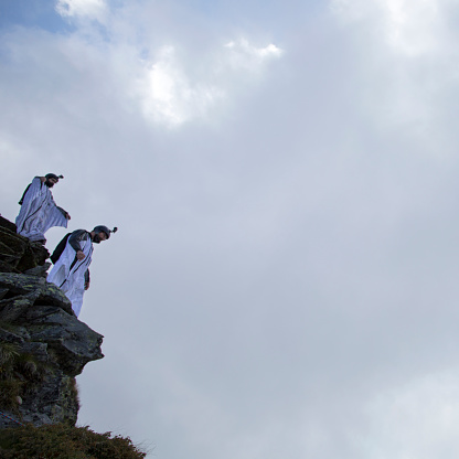 Two wingsuit jumpers about to launch, mountain summit