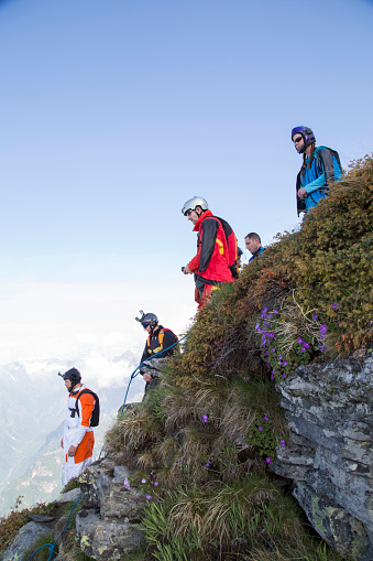 Group of wingsuit jumpers about to launch, mountain summit