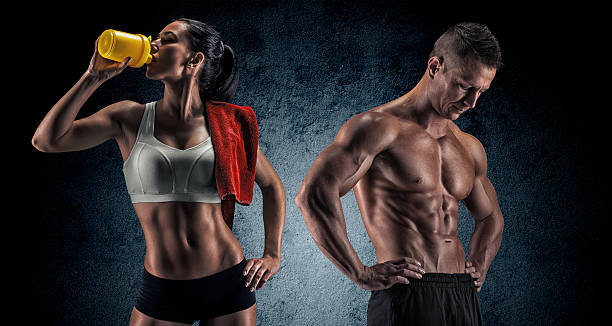 Athletic man and woman after fitness exercise Bodybuilding. Strong man and a woman posing on a dark background body building photos stock pictures, royalty-free photos & images