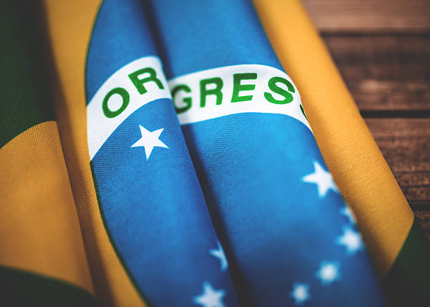 Cropped image of hand holding brazilian flag, isolated on white