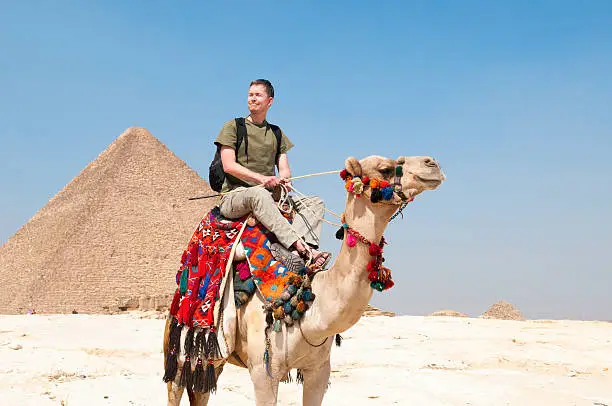 A tourist views the Pyramids of Giza from atop a camel in Cairo, Egypt