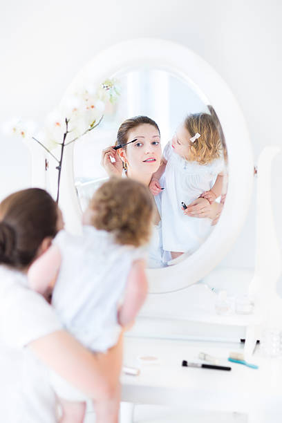 frau anwendung machen und ihr kleinkind tochter sie es - mirror mother bathroom daughter stock-fotos und bilder