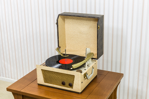 Vintage record player with vinyl album on wood table.