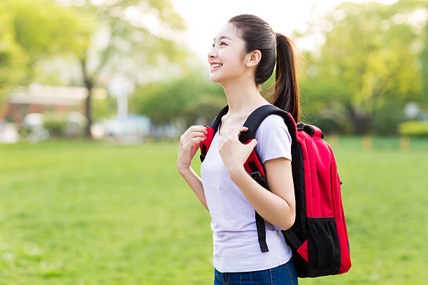 female student outdoors holding a notebook and smiling stock photo