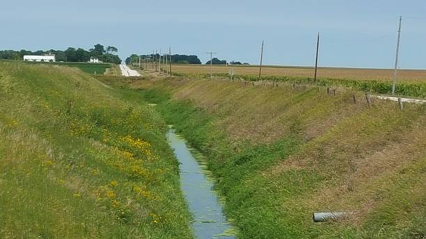 Drainage Ditch Near Northern Iowa Field This drainage ditch in northern Iowa helps drain excess water from nearby fields. Properly drained fields contribute to more productive crops.  ditch stock pictures, royalty-free photos & images