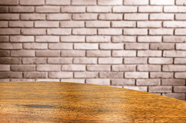 Empty wood round table and red brick wall in background