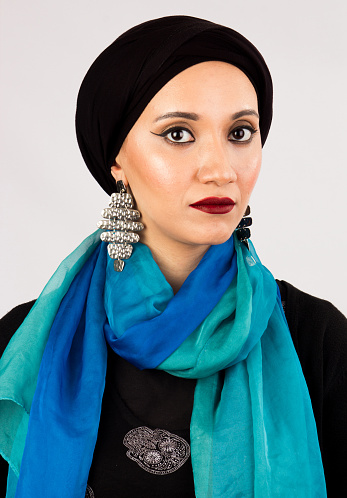 Vintage portrait of  anArabic Veiled Young woman with high fashion dark make up wearing hijab, colorful scarf and fashion earrings.
