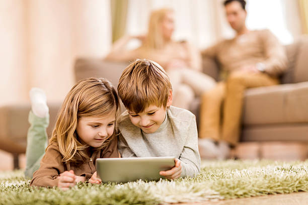 istock Children lying on the carpet and using digital tablet. 486501788