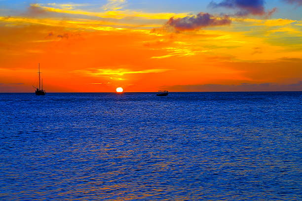 paradis sur l'île d'aruba: plage turquoise, des bateaux, spectaculaire coucher de soleil coloré, antilles néerlandaises - sailing sailboat sunset aruba photos et images de collection