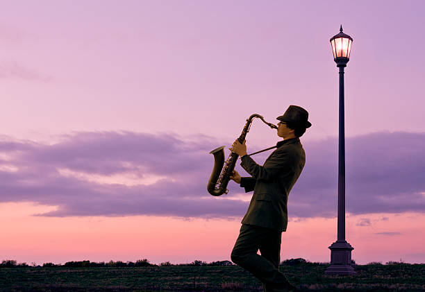 una persona giocando un sassofono accanto a strada lampada - smooth jazz foto e immagini stock