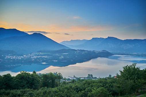 Beautiful lake in Trentino area, Northern Italy in the Alps. Left the small town Tenna and right Caldonazzo. It is early morning and there is a morning mist over the lake. The sun is close to rise from behind the mountains.