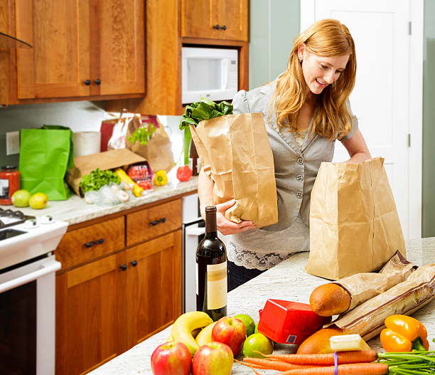 istock young woman unbagging healthy groceries in kitchen 486503157