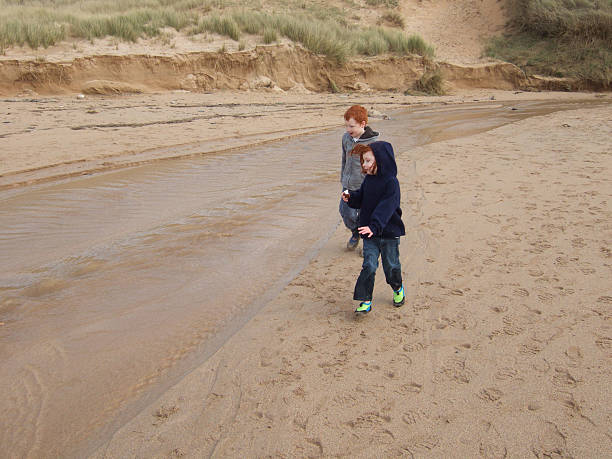 istock Image of young children walking on beach, next to stream 486504751