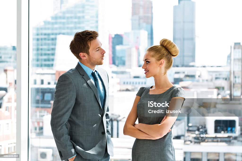 Business couple Portrait of two business people discussing in the office, with cityscape in the background. Business Stock Photo