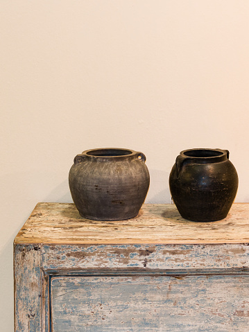 two empty pots in ethnic style on wooden old-looking cupboard