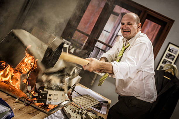 istock Mature adult businessman smashing computer on fire with hammer 486507400