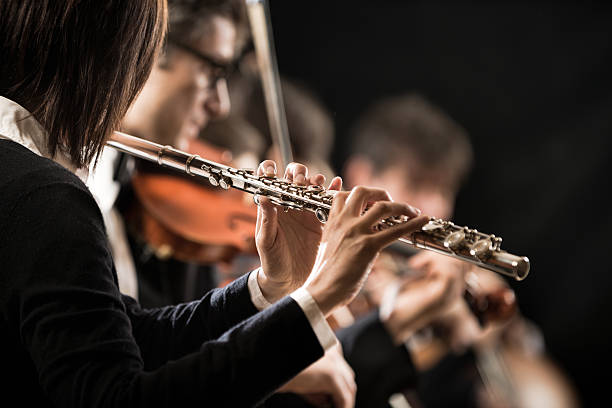 istock Female flutist with orchestra on stage 486508470