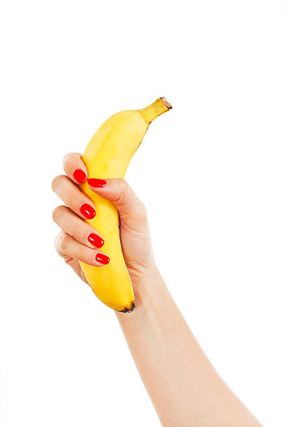 istock Female hand with red nails holding a banana 486517176