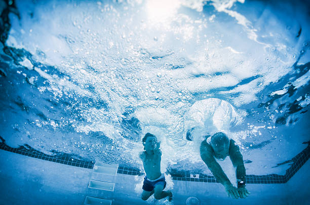 istock boy and grandpa diving into pool underwater 486517566