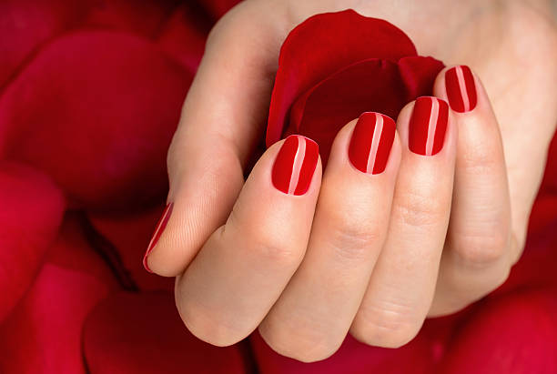 istock Beautiful female finger nails with red nail on petals. 486522219
