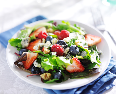 berry salad with walnuts and blue cheese on white table cloth shot close up