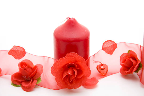 Red wax candle with rose tape on white background