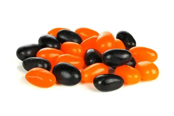 Pile of Halloween orange and black jellybeans over a white background
