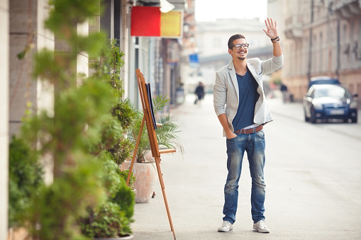 Cheerful young man waving on the street.