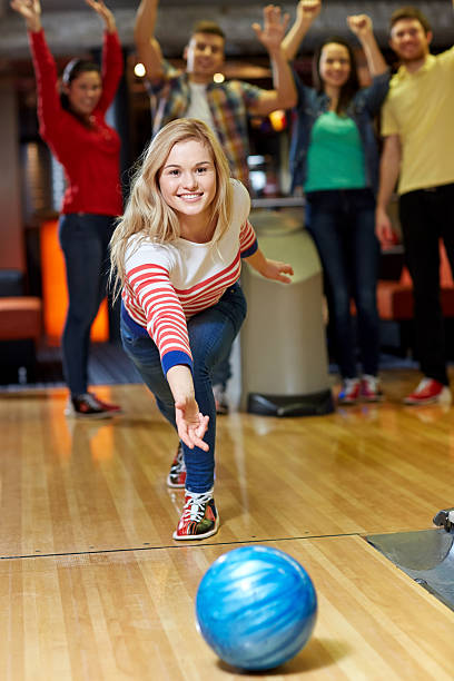 feliz mujer joven lanzar bola en club de bowling - bolo fotografías e imágenes de stock