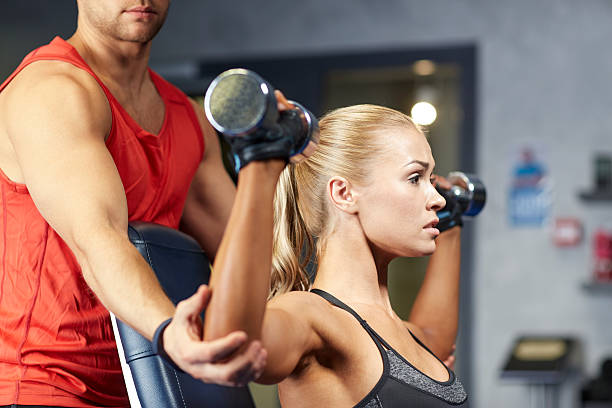 homem e mulher com halteres na academia de ginástica - flexing muscles men human muscle human arm - fotografias e filmes do acervo