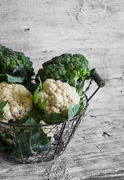 fresh cauliflower and broccoli in a vintage metal basket fresh cauliflower and broccoli in a vintage metal basket on a light wooden surface cruciferous vegetables stock pictures, royalty-free photos & images