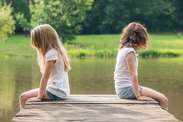 istock Two sisters sitting separately in the afternoon on the bridge 486537562