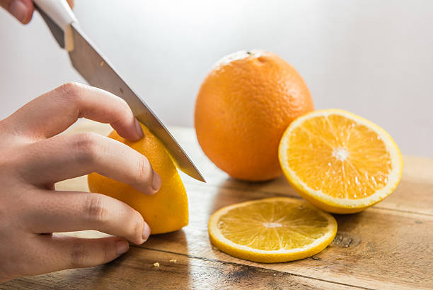 istock Hand slicing orange on wooden board 486544764