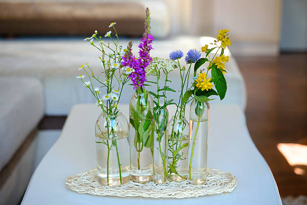 Selective focus shot of vases with flowers set on a table as a decoration for afternoon tea at the back yard.