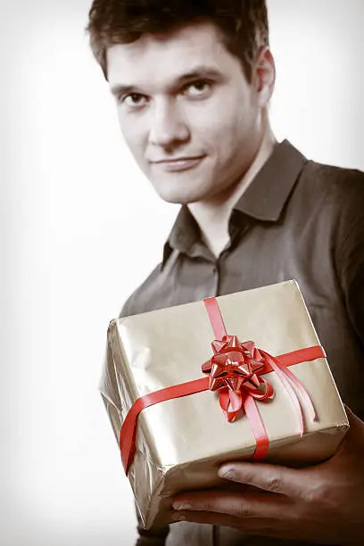 Photo of Holiday. Man giving golden gift box with ribbon