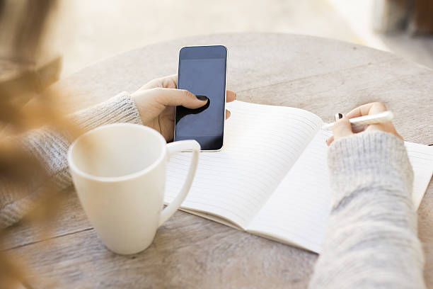 istock girl writes in a notebook, with cell phone 486548596